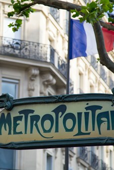 Ecriteau indiquant une bouche du métro parisien avec en arrière-plan un drapeau de la France