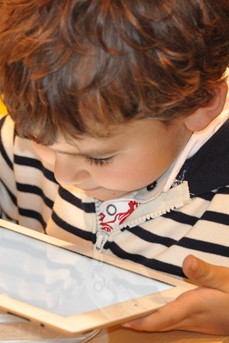 Une tablette dans les mains, un enfant regarde l'écran