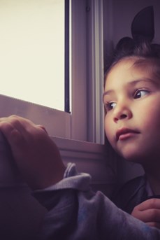 Une fillette confinée regarde par la fenêtre