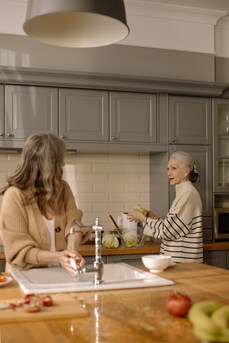 Deux femmes âgées discutent tout en cuisinant dans un habit inclusif