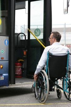 Un homme en fauteuil roulant se présente devant la porte d'un bus