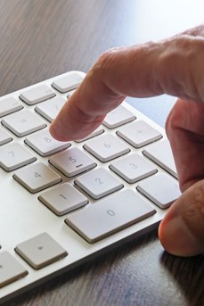 Un homme s'apprête à taper sur une touche du clavier de son ordinateur