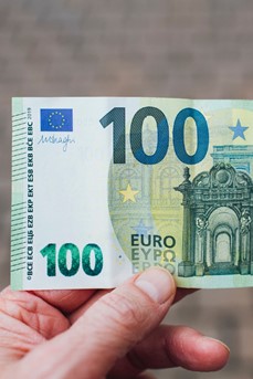 Une personne tient un billet de 100 euros dans sa main