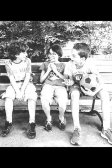 Photo en noir et blanc tirée de l'exposition « Je suis autiste et alors ? » et représentant des enfants rieurs assis sur un banc