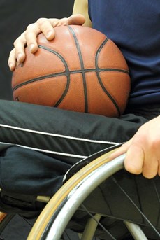 Un sportif en fauteuil roulant avec un ballon de basket posé sur ses jambes