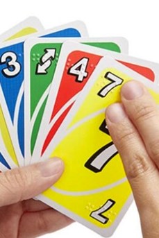Un joueur avec des cartes UNO dans la main touche les inscriptions en braille du bout des doigts