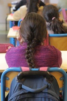 Une jeune élève est assise sagement à sa table dans la salle de classe
