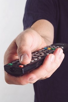 Un homme utilise une télécommande pour changer les chaînes de sa télévision