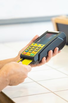 Une commerçante insère une carte bancaire dans un boitier électronique de paiement