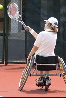 Une joueuse de tennis en fauteuil roulant frappe dans la balle
