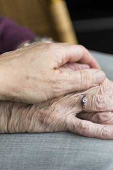 Une aidante pose sa main sur celle d'une personne âgée