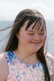 Une jeune femme atteinte de trisomie 21 avec les cheveux dans le vent