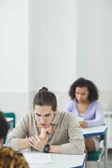 Des étudiants assis chacun à une table se concentrent durant un examen