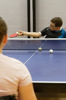 Un jeune en situation de handicap joue au tennis de table lors du stage