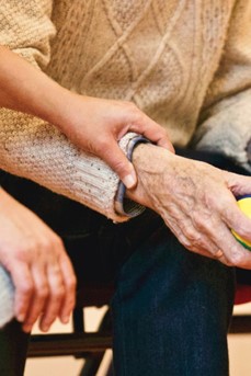 Un proche pose la main sur le bras d'une personne âgée