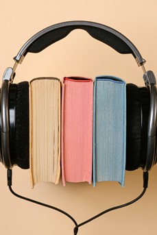 Un casque audio noir entoure trois livres