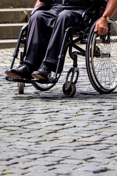 Un homme en fauteuil roulant dans une rue pavée