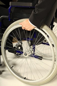 Une personne handicapée pose sa main sur la roue de son fauteuil roulant