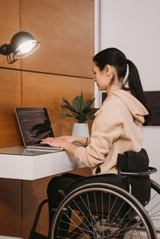 Une femme en chaise roulante travaille sur son ordinateur portable