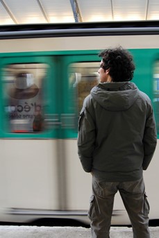 Un homme debout sur le quai regarde un métro parisien arriver