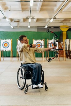 Un jeune en chaise roulante pratique le tir à l'arc dans un club