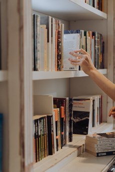 Une personne prend un livre dans l'étagère d'une librairie