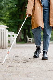 Une femme aveugle utilise une canne blanche en se promenant dans un parc