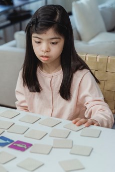 Une jeune fille atteinte de trisomie 21 apprend à reconnaître des objets grâce à des cartes posées sur une table
