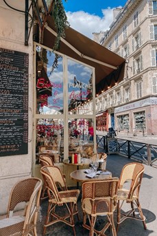 Terrasse d'un bistrot à Paris avec des tables, des chaises et une ardoise avec la liste des plats
