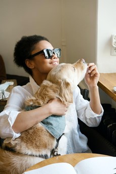Une jeune femme déficiente visuelle joue avec son chien guide
