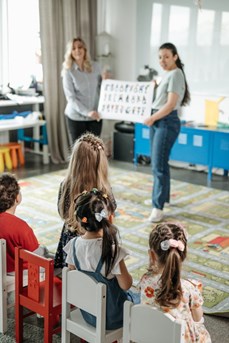 Dans une salle de classe d'une école primaire, des institutrices montrent un panneau avec l'alphabet à des écoliers