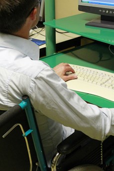 Un travailleur handicapé en chaise roulante utilise un ordinateur sur son poste de travail