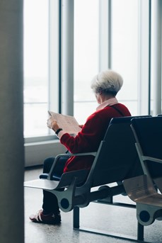 Une femme âgée lit le journal dans une salle d'attente