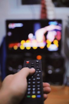 Une personne tient une télécommande dans la main pour changer les chaînes de sa télévision