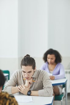 Des étudiants assis chacun à une table se concentrent durant un examen