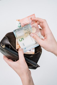 Une personne sort des billets en euros de son porte-monnaie