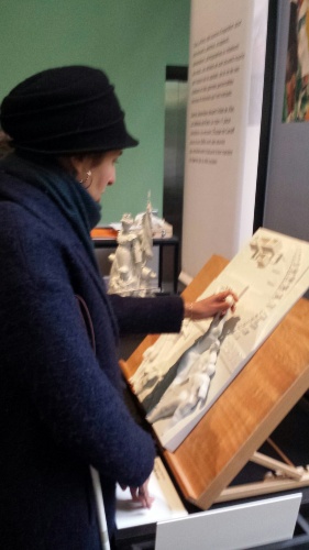 Une visiteuse découvre une œuvre en touchant sa représentation tactile
