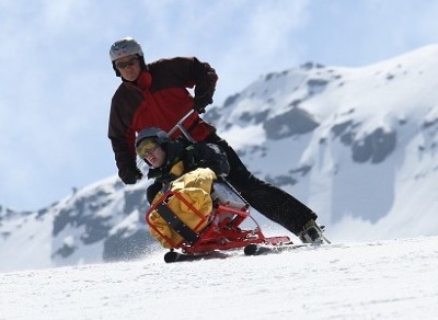 Une personne handicapée est installée dans un tandem-ski conduit par un accompagnant