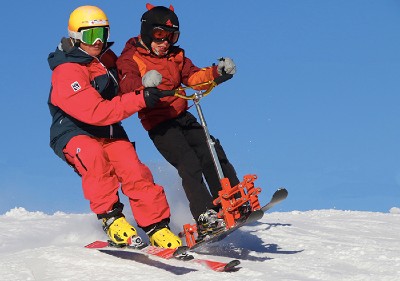 Un accompagnant skieur aide un jeune garçon qui conduit un trotti-ski