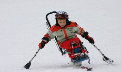 Un jeune skieur handicapé utilisant un uniski et des stabilos